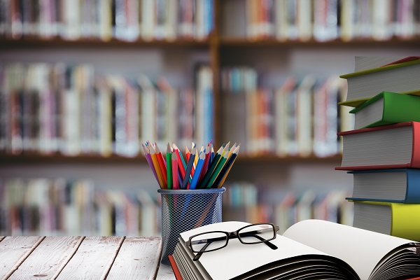 digital composite of school materials on table with library background