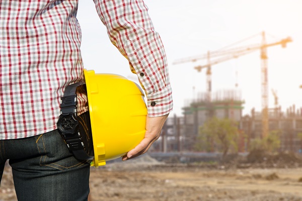 Hand's engineer worker holding yellow safety helmet with buildin